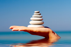 Hand holding pebbles in pyramid shape symbolizing life balance.
